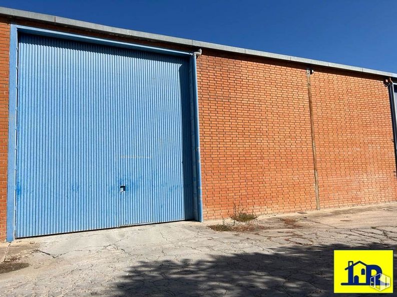 Industrial for rent at Avenida Cruz Roja, Cuenca, 16002 with door, building, property, sky, road surface, asphalt, brick, rectangle, wood and shade around